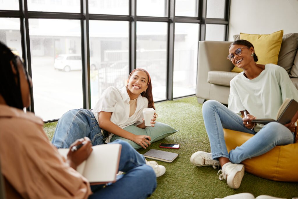 Writing, studying and collaboration student friends in university lounge for a group project, teamwork and planning schedule. Young women relax with coffee and brainstorming ideas and time management
