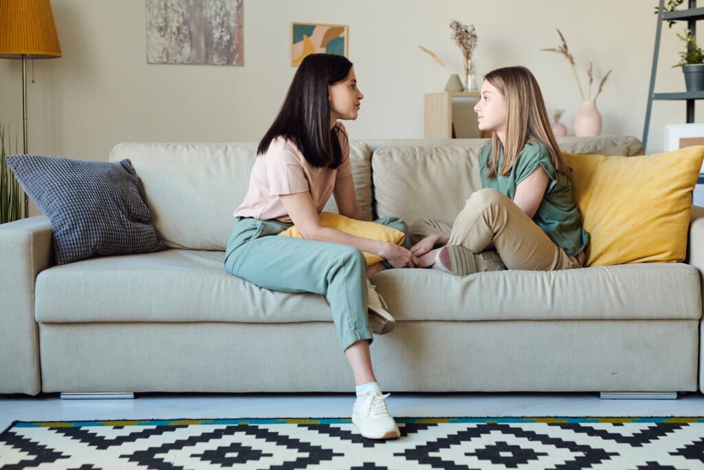Young contemporary woman and her daughter in casualwear talking on couch
