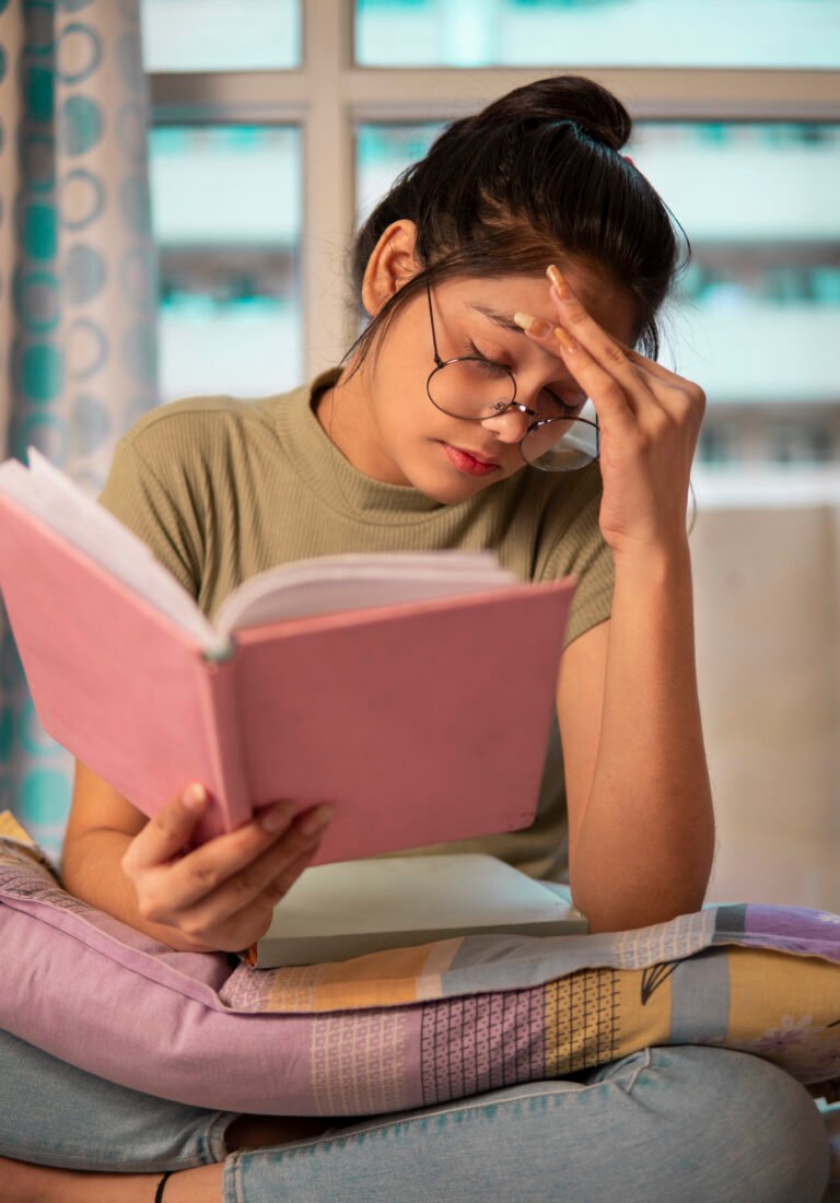 Young woman suffering from migraine while reading a book.