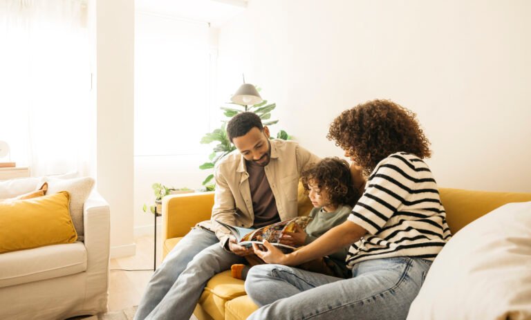 Family enjoying reading stories together on a cozy living room couch.