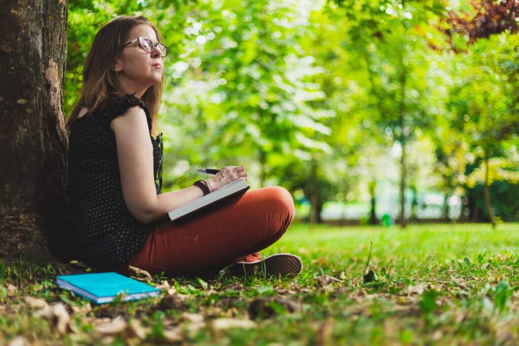 Woman taking notes while making research from a book outdoors