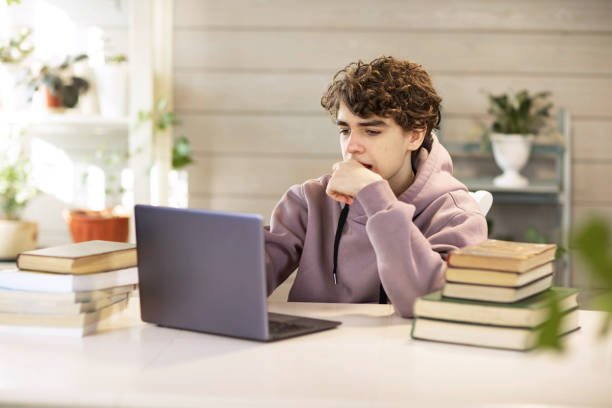 young man, student studying at home, looking at a laptop. High quality photo