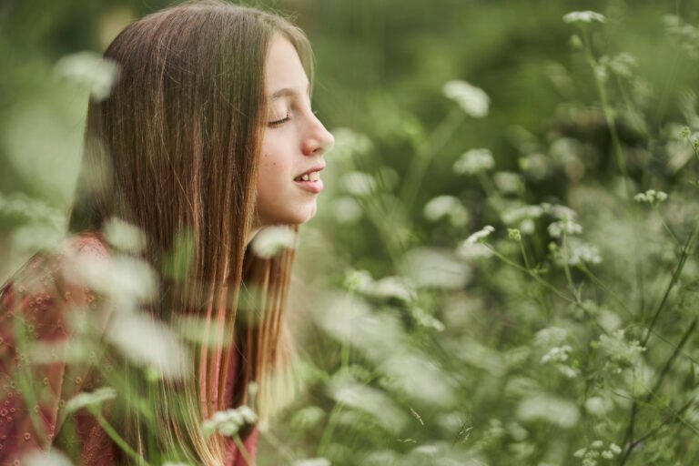 teenage girl among flowers enjoying the scent