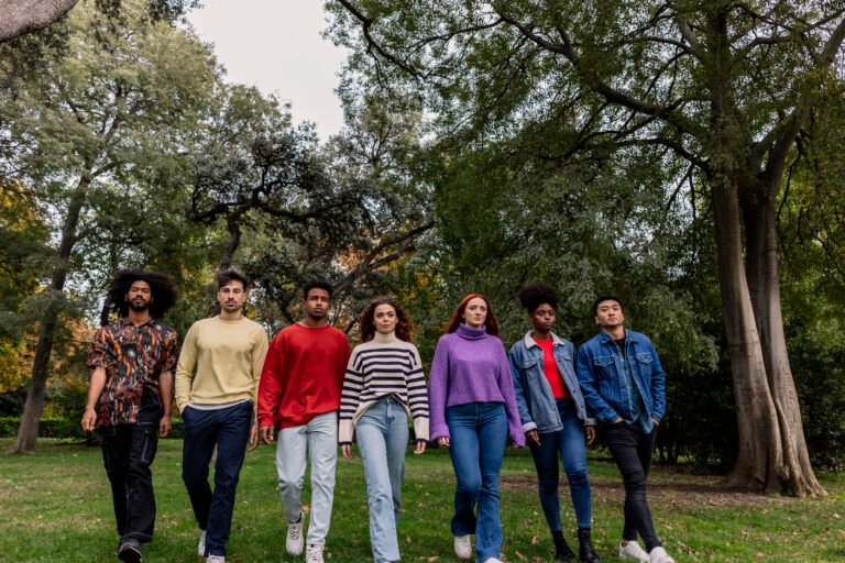 group of multiethnic friends in a row walking towards camera with security
