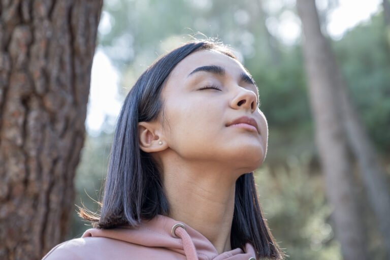 Young girl breathing relaxed in the forest opening and closing her eyes