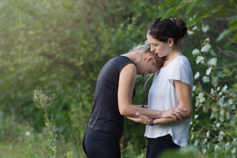 Young women hug in nature. A woman provides psychological assistance to her friend at a yoga session outdoors. The concept of meditation, spiritual practices. Copyspace