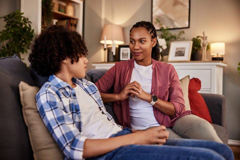 A pretty African-American woman talking with her teenage son at home.