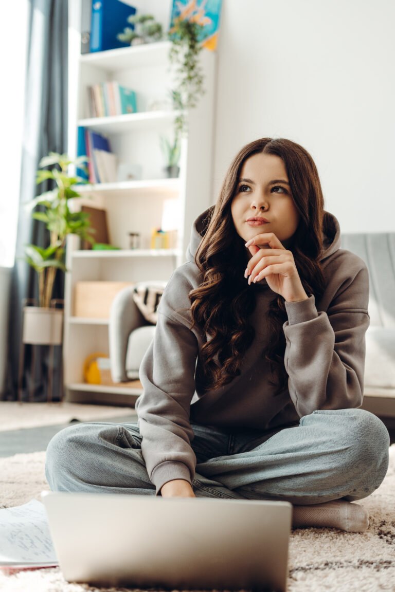 Teenager girl thinking and working on laptop at home
