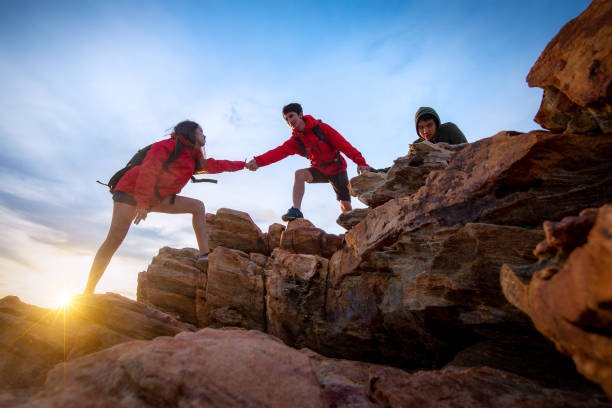 Hikers climbing up on the mountain,team work and helping concept.