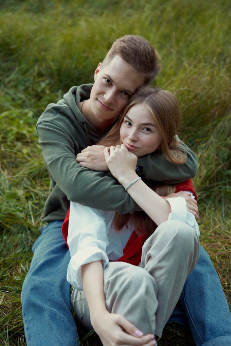 young teen couple laying on a grass on a field in september
