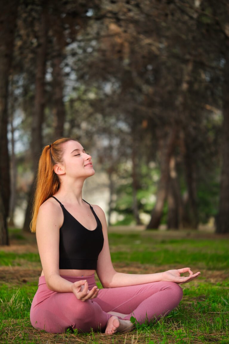 Redhead young woman meditating in a forest.