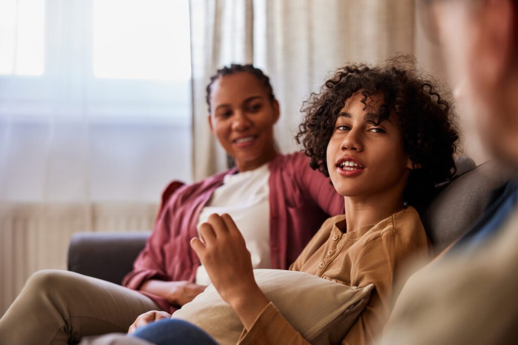 Handsome teenager with curly hair talking to his parents at home, close-up.