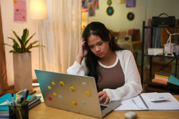 School girl reading article for school project on laptop at home