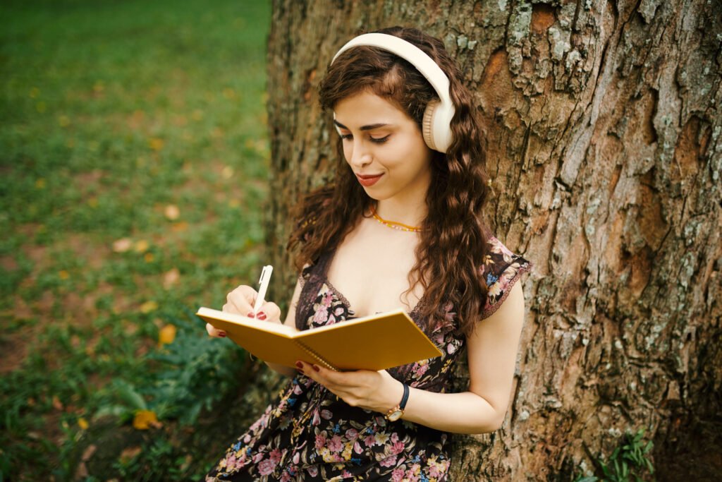 Girl making notes in diary under tree