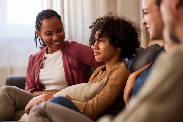 Diverse multigeneration family sitting a couch at home, relaxing and chatting.