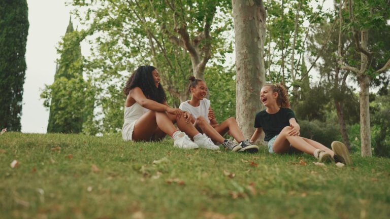 Three girls friends pre-teenage sit on the grass in the park and emotionally talking. Three teenagers on the outdoors