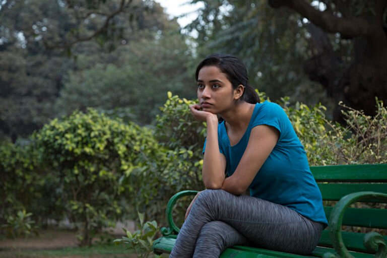 Unhappy girl sitting at bench - Stock image