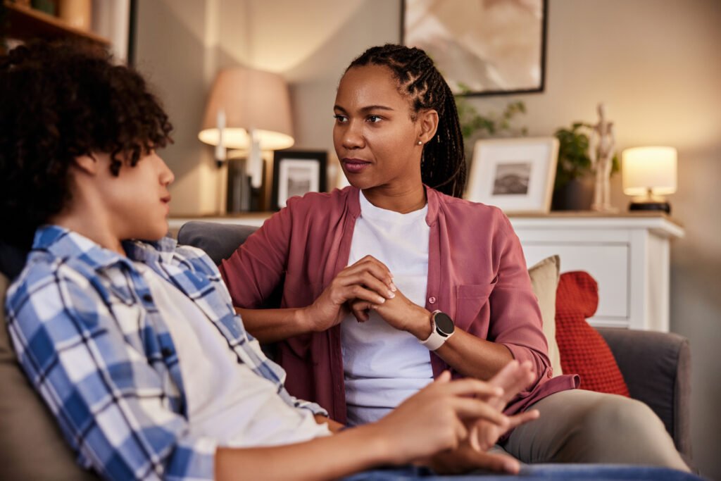 A pretty African-American woman talking with her teenage son at home.