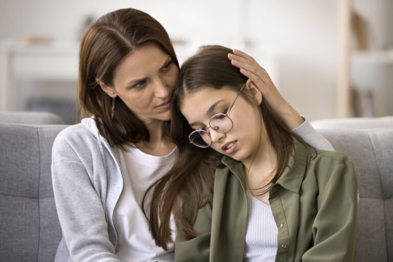 Concerned mother hugging upset teenager daughter child at home