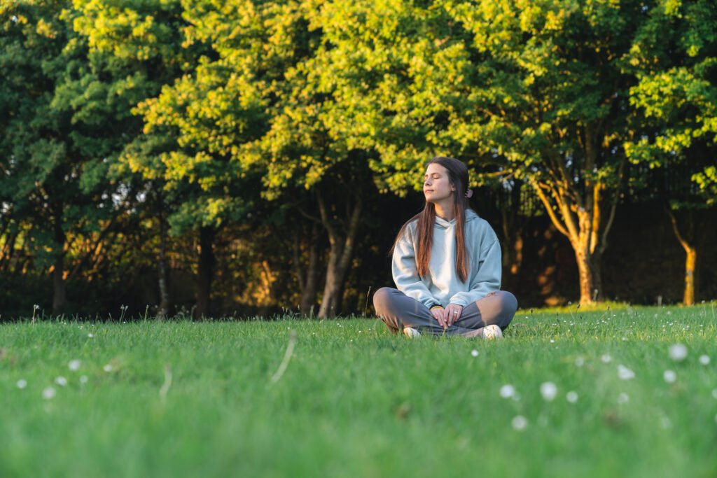 Young woman meditating in a peaceful park setting at sunset
