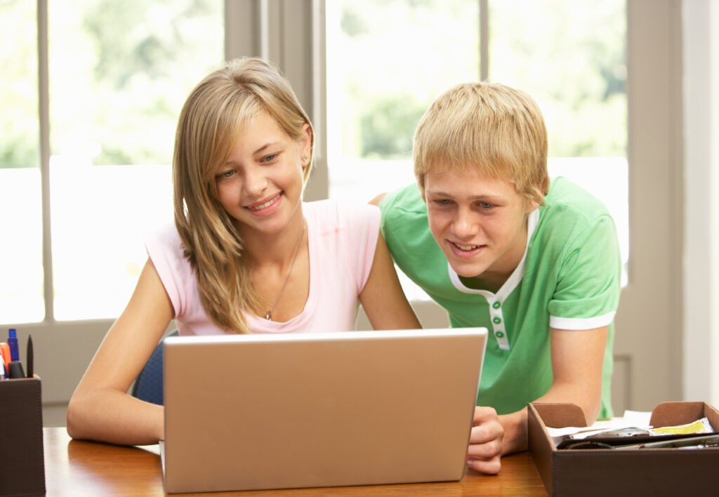 Two Teenagers Using Laptop At Home