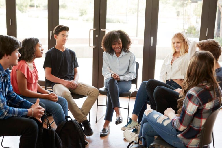 Female Tutor Leading Discussion Group Amongst High School Pupils