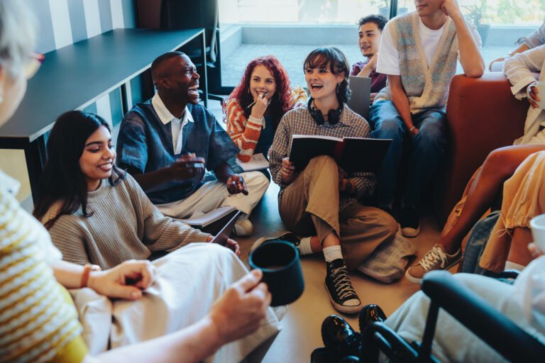 Diverse group of students engaged in a lively classroom discussion with notebooks, seated comfortably in an informal learning environment