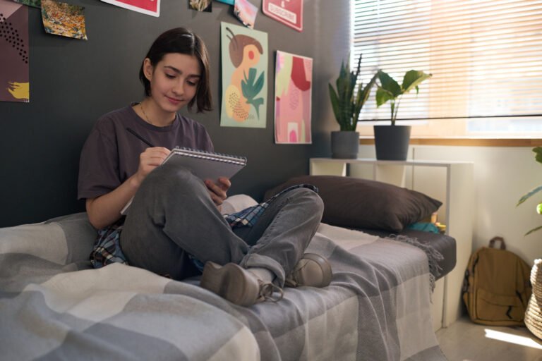 Teen Girl on Bed Drawing in Sketchbook