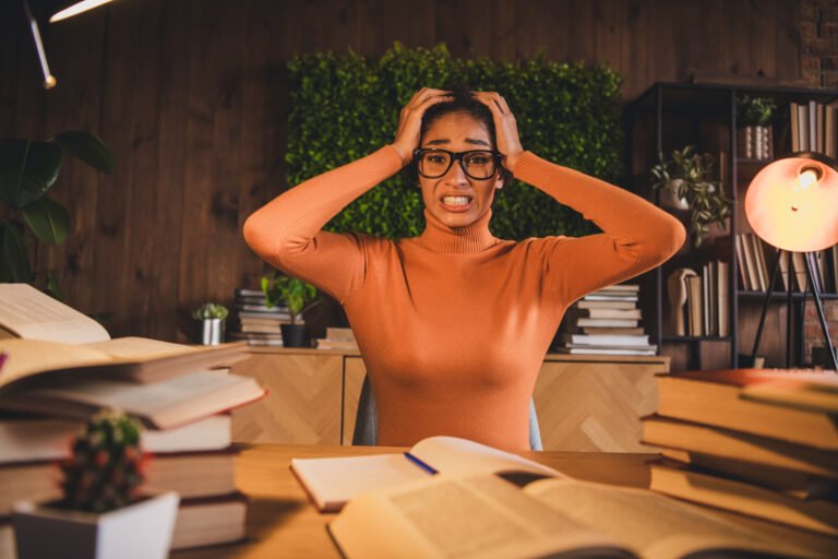 Stressed student in a cozy home setting with books, expressing frustration during a late study session.