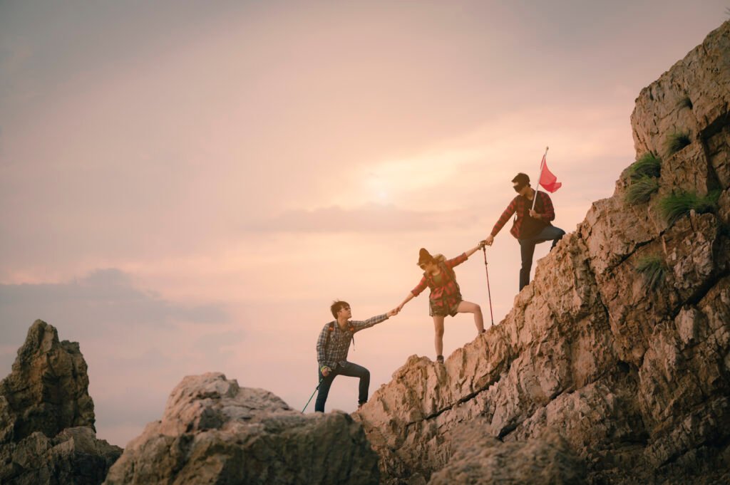 Low Angle View Of Friends Holding Hands While Climbing On Mountain