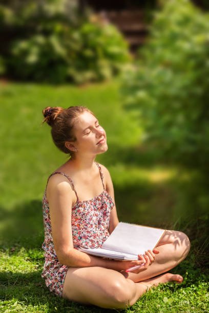 Portrait of a healthy young woman with glasses with a book on the grass