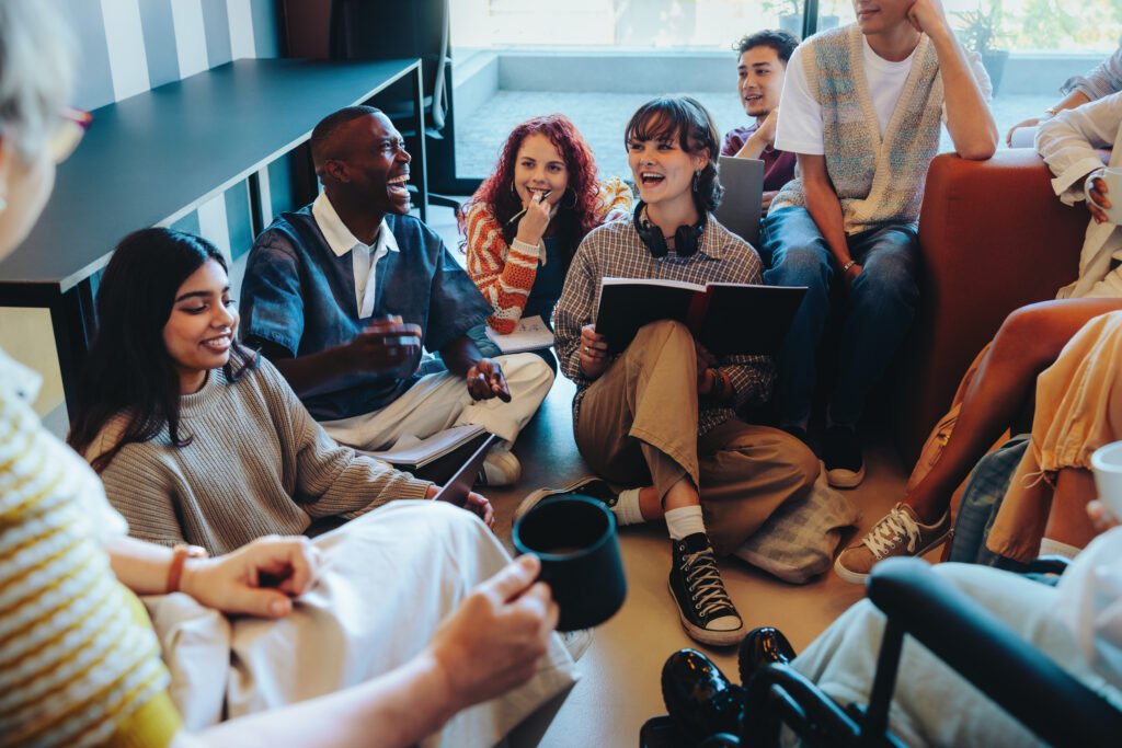 Diverse group of students engaged in a lively classroom discussion with notebooks, seated comfortably in an informal learning environment