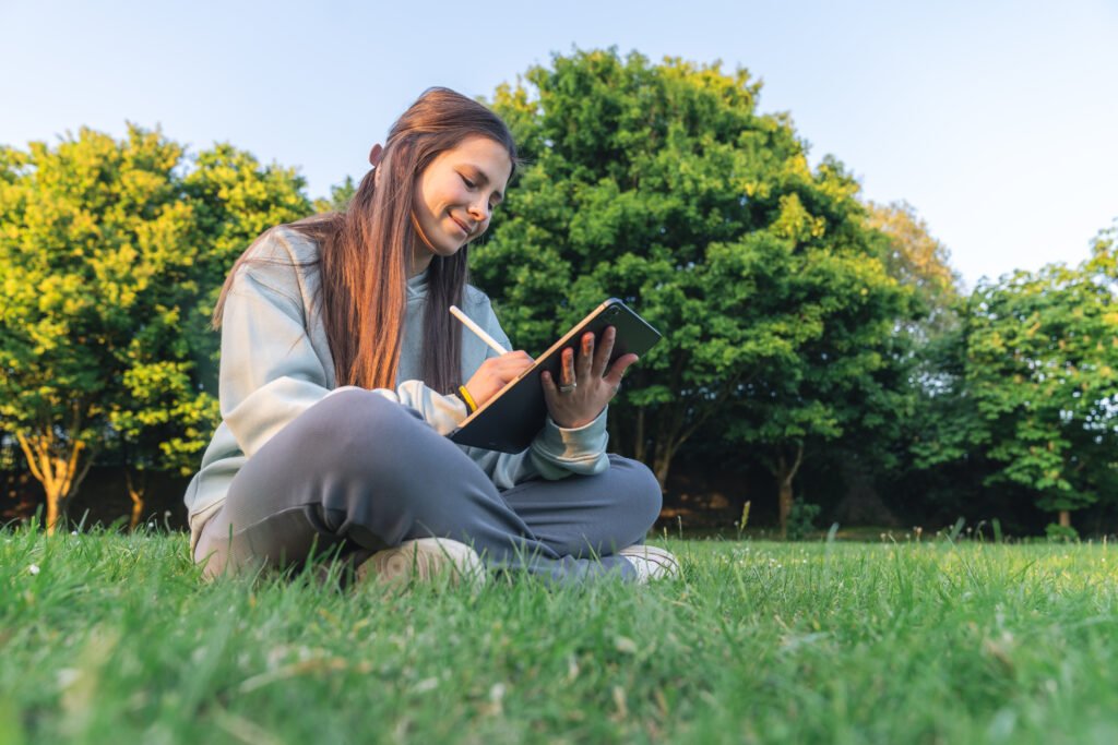 Young woman writing in a notebook outdoors