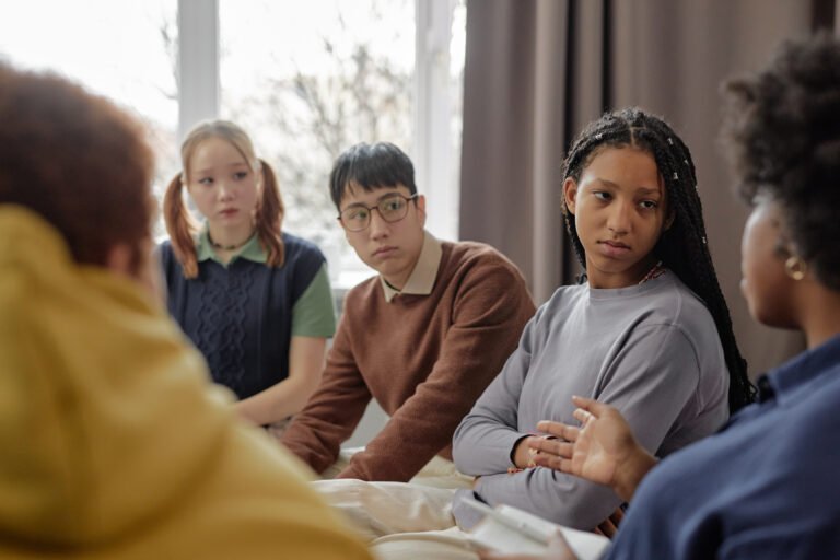 Diverse Group of Teen Children Listening to Therapist in Support Session