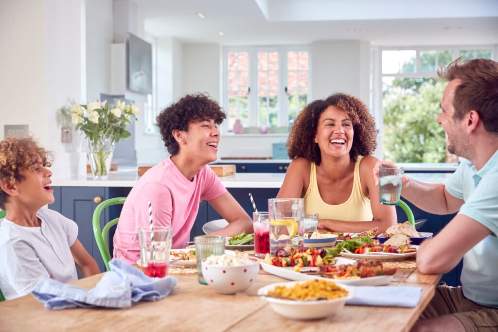 Family Sitting Around Table At Home Eating Meal Together