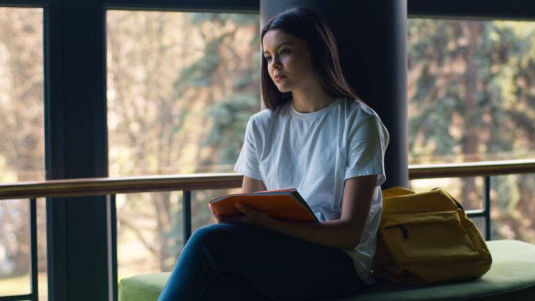 Caucasian pensive thinking thoughtful girl female woman student pupil schoolgirl lady study education outside in city near school university college looking at notebook holding copybook textbook think