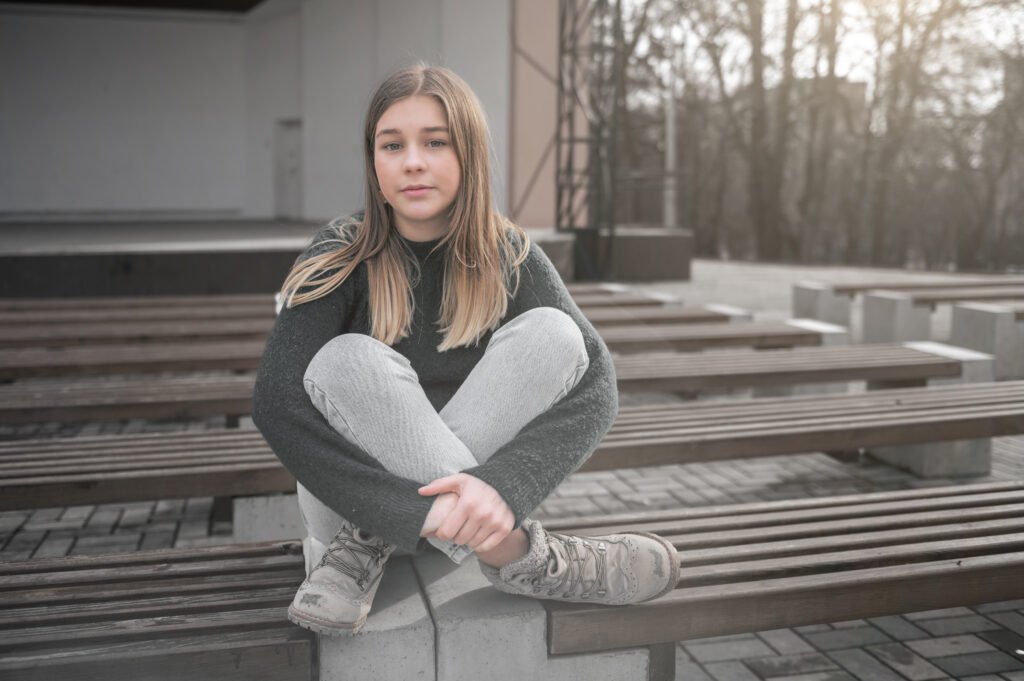 Lonely sad girl. Sad teen girl on a bench in the park. Single girl outdoor.