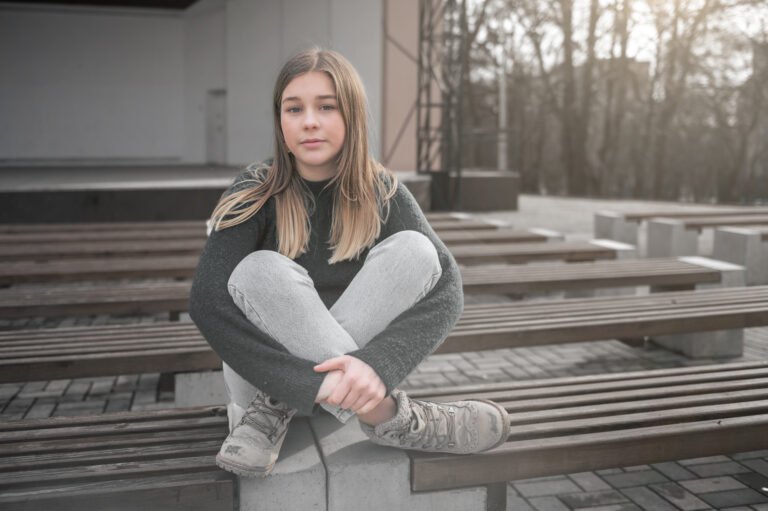 Lonely sad girl. Sad teen girl on a bench in the park. Single girl outdoor.