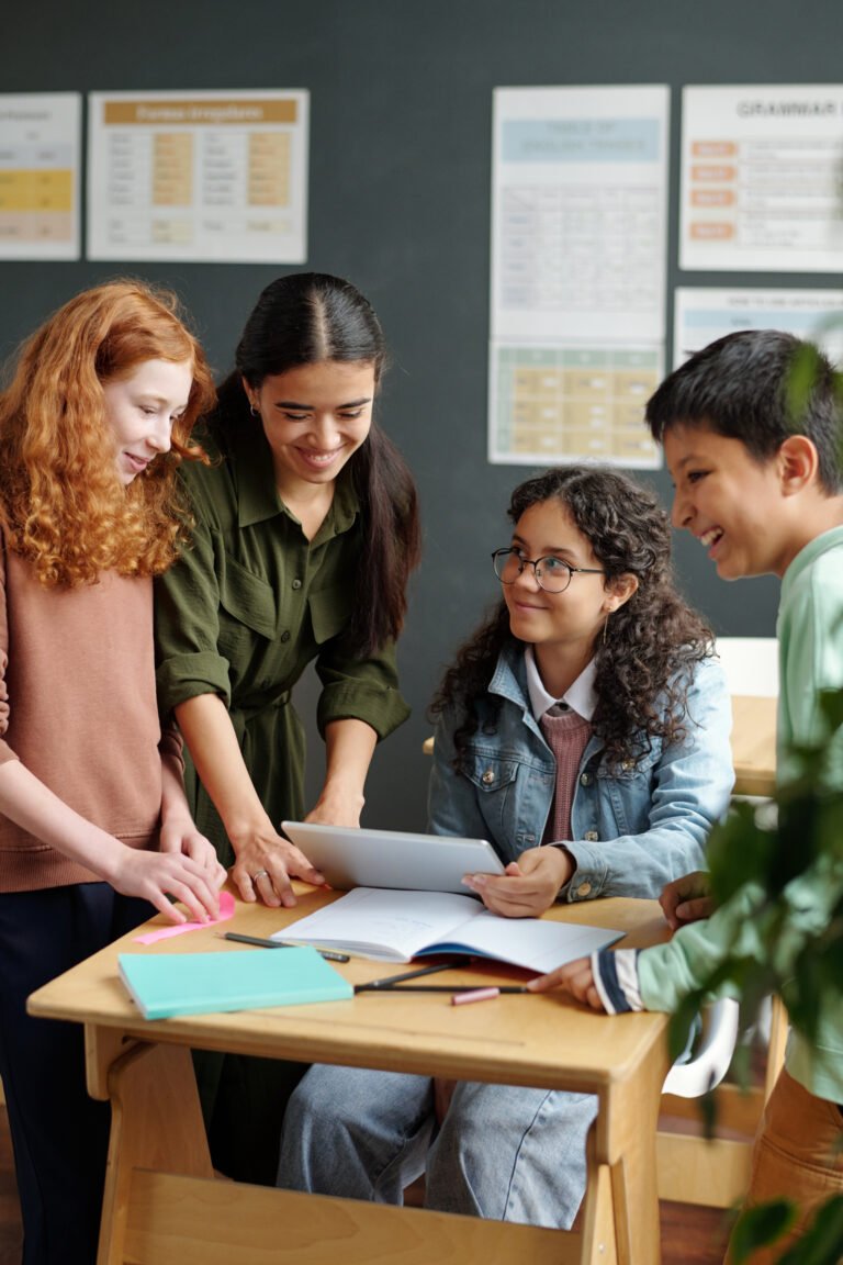 Happy intercultural pupils and teacher discussing online video at lesson