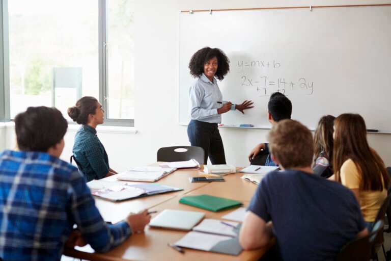 Female High School Tutor At Whiteboard Teaching Maths Class