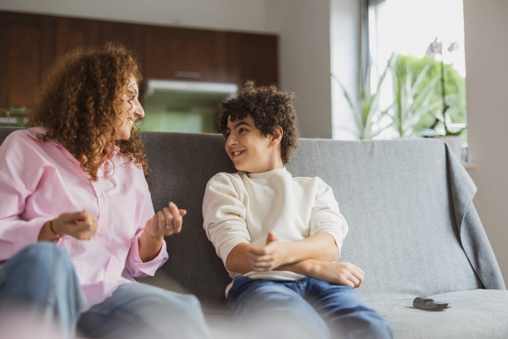 Happy mother and son sitting on sofa in living room at home