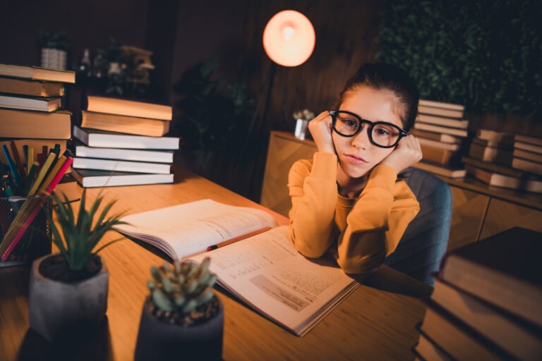 Young girl studying at home in a casual setting surrounded by books and stationery