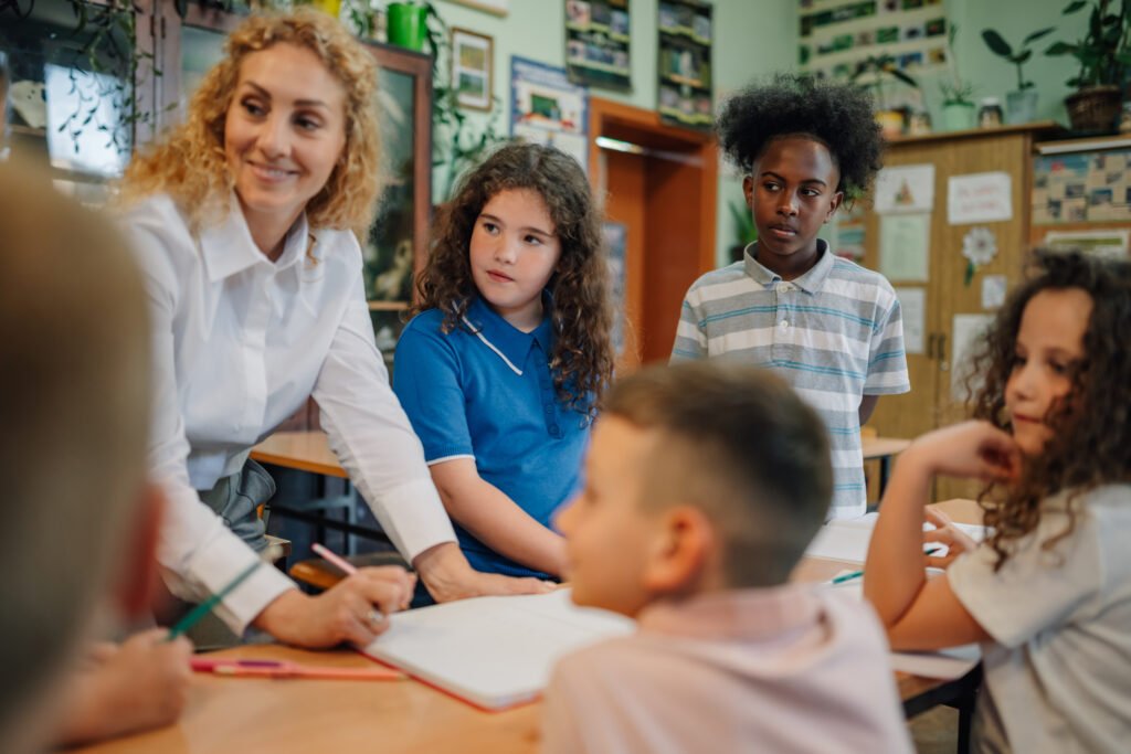 Teacher helping elementary school students studying in classroom