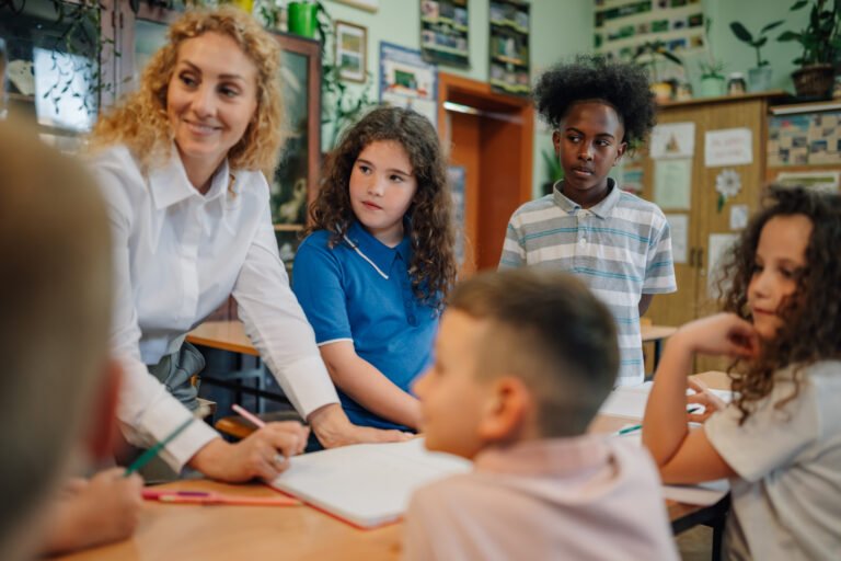 Teacher helping elementary school students studying in classroom