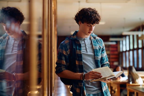High school student learning from a book in library. Copy space.