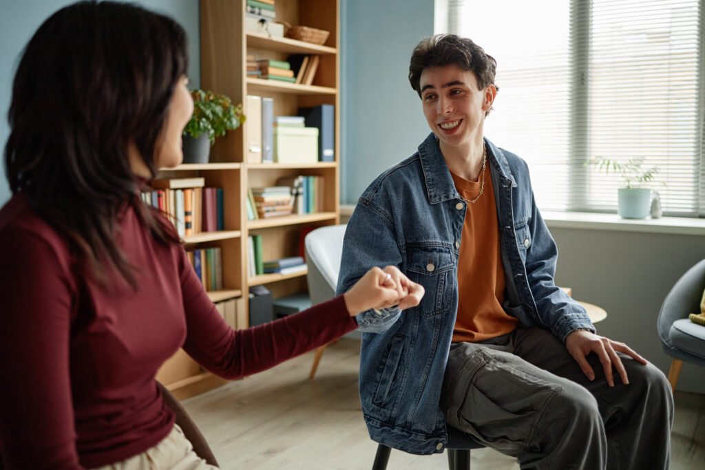 Teenage Boy Smiling While Attending Counseling Session with Female Counselor