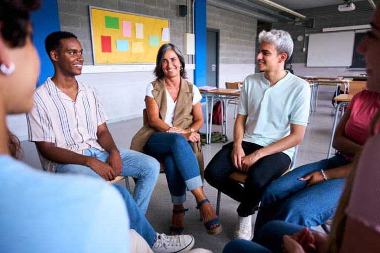 Diverse group of high school students sitting on chairs in a circle and interacting during a lesson