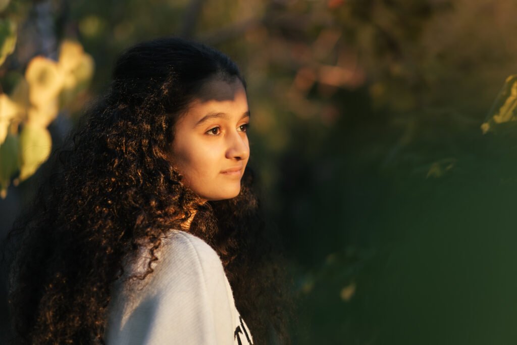 Dreamy scene. A closeup of 13 years old girl watching the sunset through the trees and sunlight touching on her face