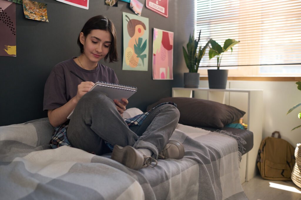 Teen Girl on Bed Drawing in Sketchbook