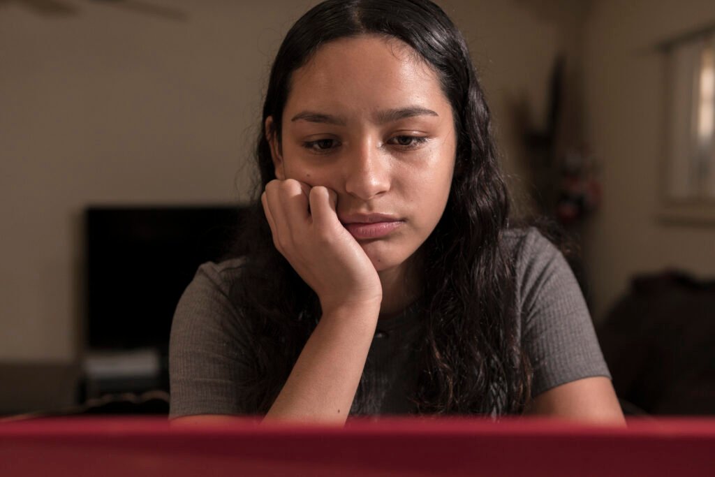 A bored teenager looking to her laptop
